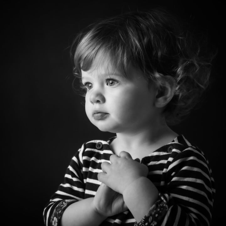 black and white study of toddler against dark background