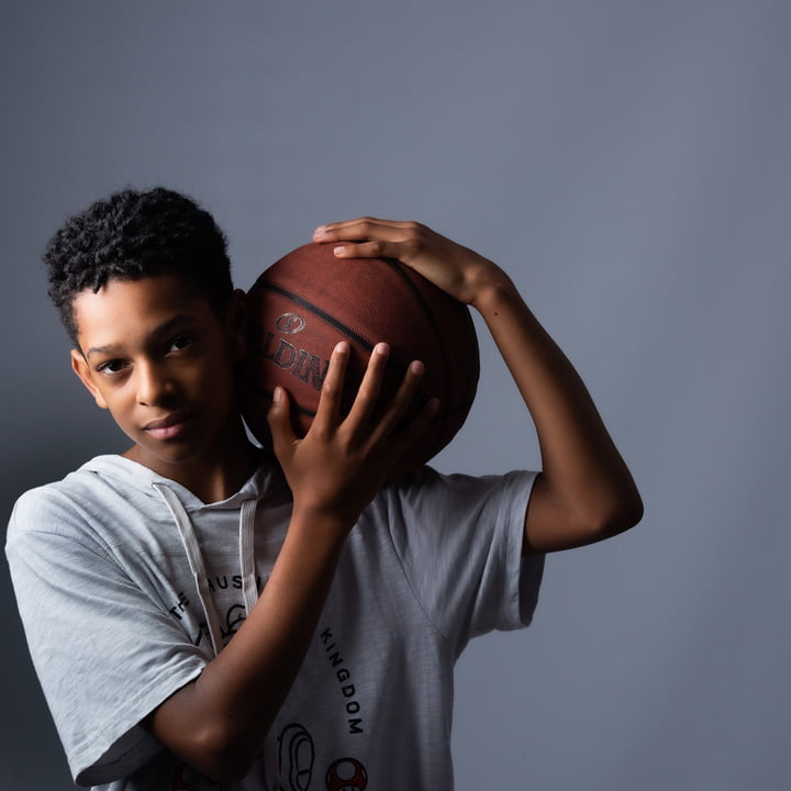 young basketball player holding ball in artistic pose